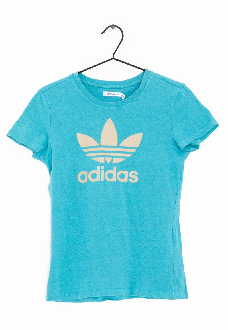 Tyrkysové bavlněné tričko s krátkým rukávem, které má velké béžové logo Adidas a tři vodorovné pruhy nad logem.