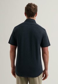 Korte mouwen overhemd in donker marineblauwe stof. Kenmerkt zich door een klassieke kraag, rechte snit en een naadloos ontwerp met een zachte textuur.