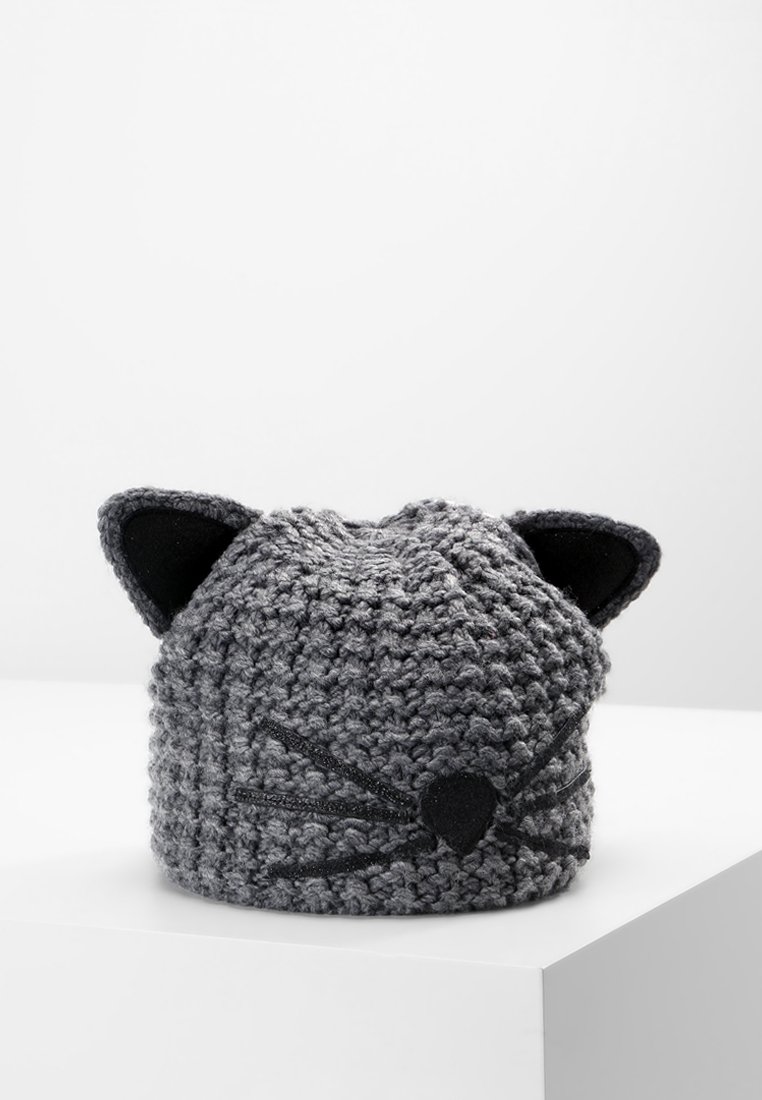 Bonnet gris tricoté avec des oreilles, un nez et des moustaches de chat noirs, présenté sur une surface blanche avec un fond uni.