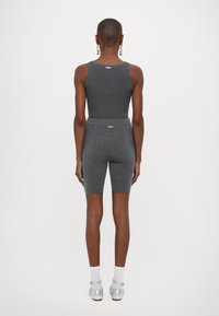 Sivý rebrovaný športový crop top v kombinácii s biker šortkami v rovnakej farbe. Minimalistický dizajn; priliehavý strih; elastický pás; obsahuje reflexný detail loga.