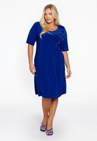 Korte mouwen jurk van effen blauwe stof, met ruches aan de linker schouder. Knielang, ontspannen pasvorm met een soepele textuur.