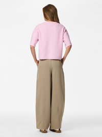 Light pink knitted sweater with short sleeves, paired with loose beige trousers. Sweater features a cropped design and ribbed texture.