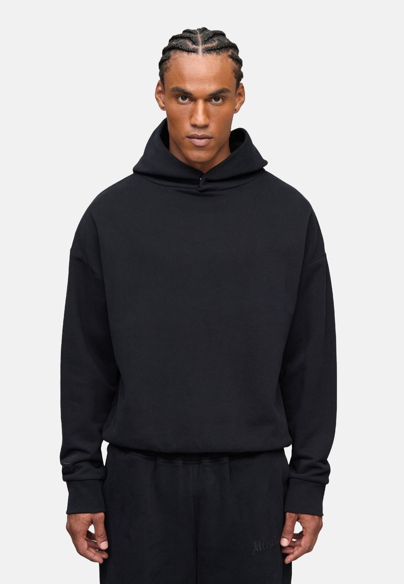 Sudadera negra con capucha en un corte holgado. Confeccionada en una tela suave, con mangas largas y puños acanalados. Presenta un sutil detalle de logo en el dobladillo.