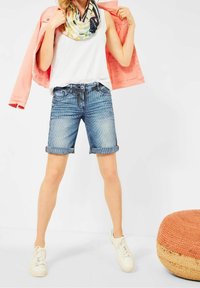 Denimowe szorty bermudy w niebiesko-białą paski, z podwiniętym dołem, w połączeniu z białym topem na ramiączkach i kwiecistym szalikiem, pod różową kurtką.