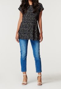 Marinblå blommönstrad tunika med korta ärmar, samlad midja, i kombination med ljusblå skinny jeans och nakna ankelremmar.