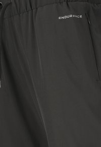 Sorte sportsshorts med elastisk talje, snøre, lynlåslomme og "ENDURANCE"-logo på højre forside.