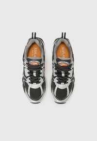 Chaussures de sport noir et gris avec une tige en mesh, accents argentés, bout rond et lacets noirs. L'intérieur est doté d'une semelle intérieure orange avec le logo de la marque.