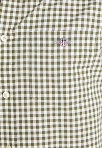 Camicia a quadri verde e bianca con taschino sul petto dotato di logo ricamato e bottoni bianchi. Tessuto in cotone, motivo testurizzato.