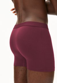Bordeauxrote Boxershorts aus weichem Material, mit einem glatten Bund, eng anliegender Passform und nahtlosen Beinausschnitten. Keine sichtbaren Muster oder Logos.