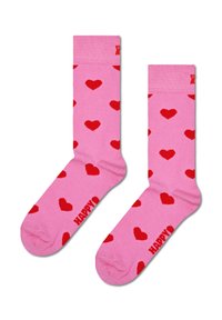 Chaussettes roses avec un motif de cœurs rouges, présentant un design tricoté et le texte "HAPPY" en rouge au niveau de la cheville. Douces, de style mi-longue à mi-mollet.