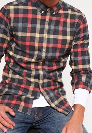 Camisa de botones con un patrón de cuadros en colores gris, rojo y amarillo. Hecha de un material suave, con cuello y mangas largas. Botones marrones.