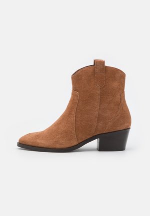 Bottine en daim marron avec talon bloc bas et languette de tirage, style Western classique, vue de côté sur fond blanc.