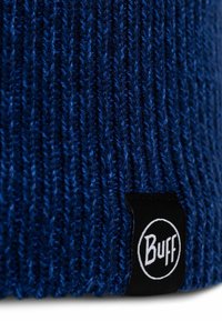 Knitted blue beanie hat made from soft yarn, featuring a ribbed texture and a black label with white "Buff" logo on the side.