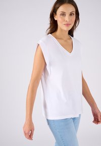 Top maniche corte bianco a V con un taglio rilassato, realizzato in morbido cotone, caratterizzato da cuciture decorative sottili attorno al collo.