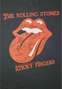 Camiseta negra con un gran gráfico de lengua y labios rojos, con acentos y texto en blanco que dice "THE ROLLING STONES" y "STICKY FINGERS."