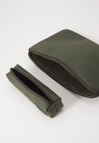 Two green bags made of smooth, durable material; one large rectangular pouch with a zipper and a smaller zippered pencil case beside it.