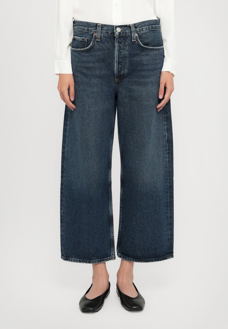Wide-leg dark blue denim jeans with a classic five-pocket design, featuring a button and zip fly at the front. Smooth texture, straight cut.