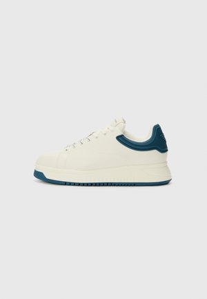 Baskets en cuir blanc avec un accent texturé bleu sur le talon, dotées d'une semelle en caoutchouc durable et d'un design classique à lacets.