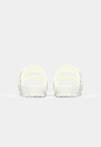 White rubber sandals with open-back design, featuring two adjustable straps and a textured sole. Smooth finish and lightweight construction.