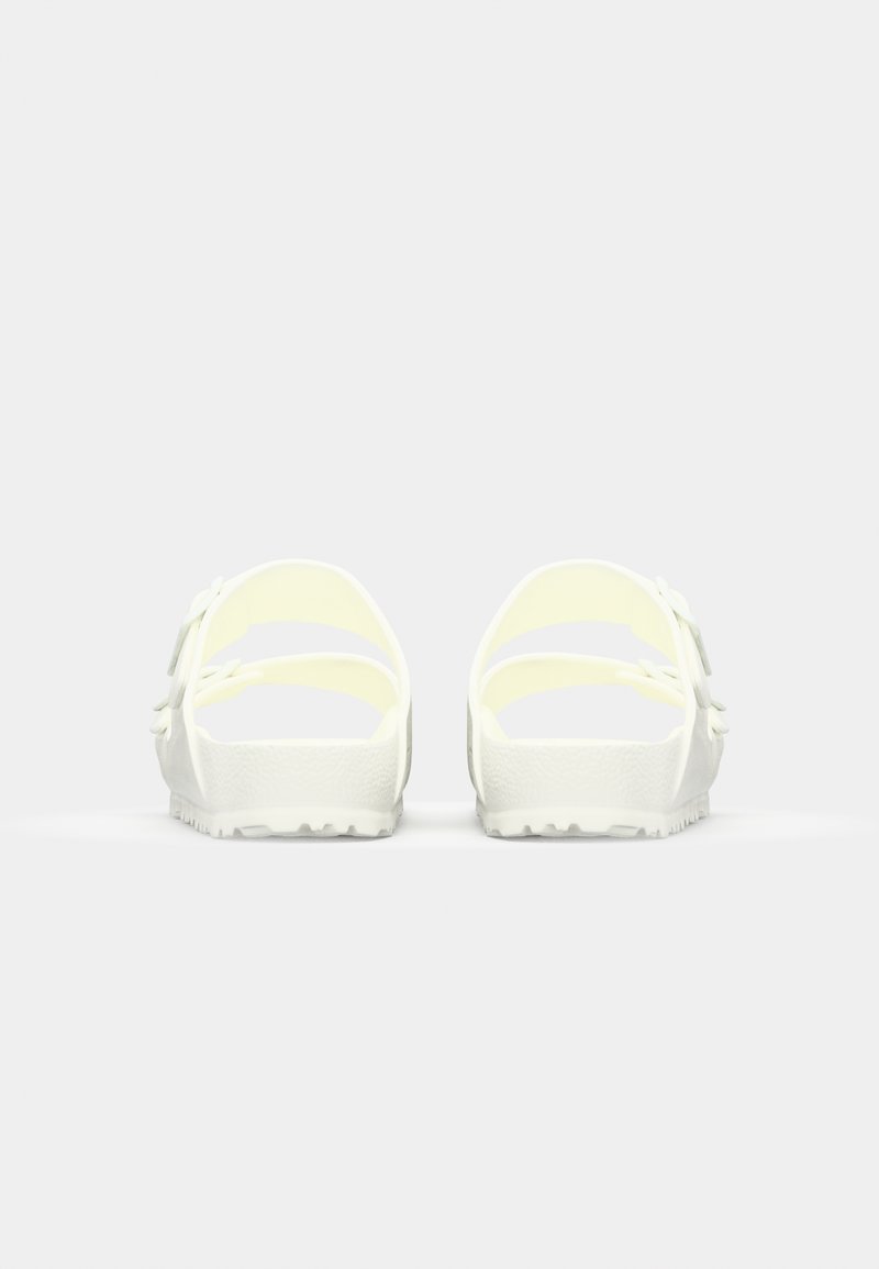 Sandalias de goma blancas con diseño de espalda abierta, que cuentan con dos correas ajustables y una suela texturizada. Acabado suave y construcción ligera.