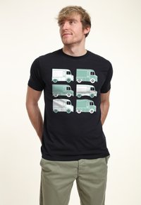 Svart t-shirt med sex stiliserade lastbilsillustrationer i ljusgrön och vit, ordnade i två rader med runda hjul synliga.