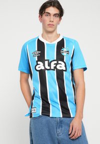 Camiseta de fútbol a rayas azul y negra con el logo "alfa" y el emblema del club. Mangas cortas y corte relajado, hecha de un tejido ligero.