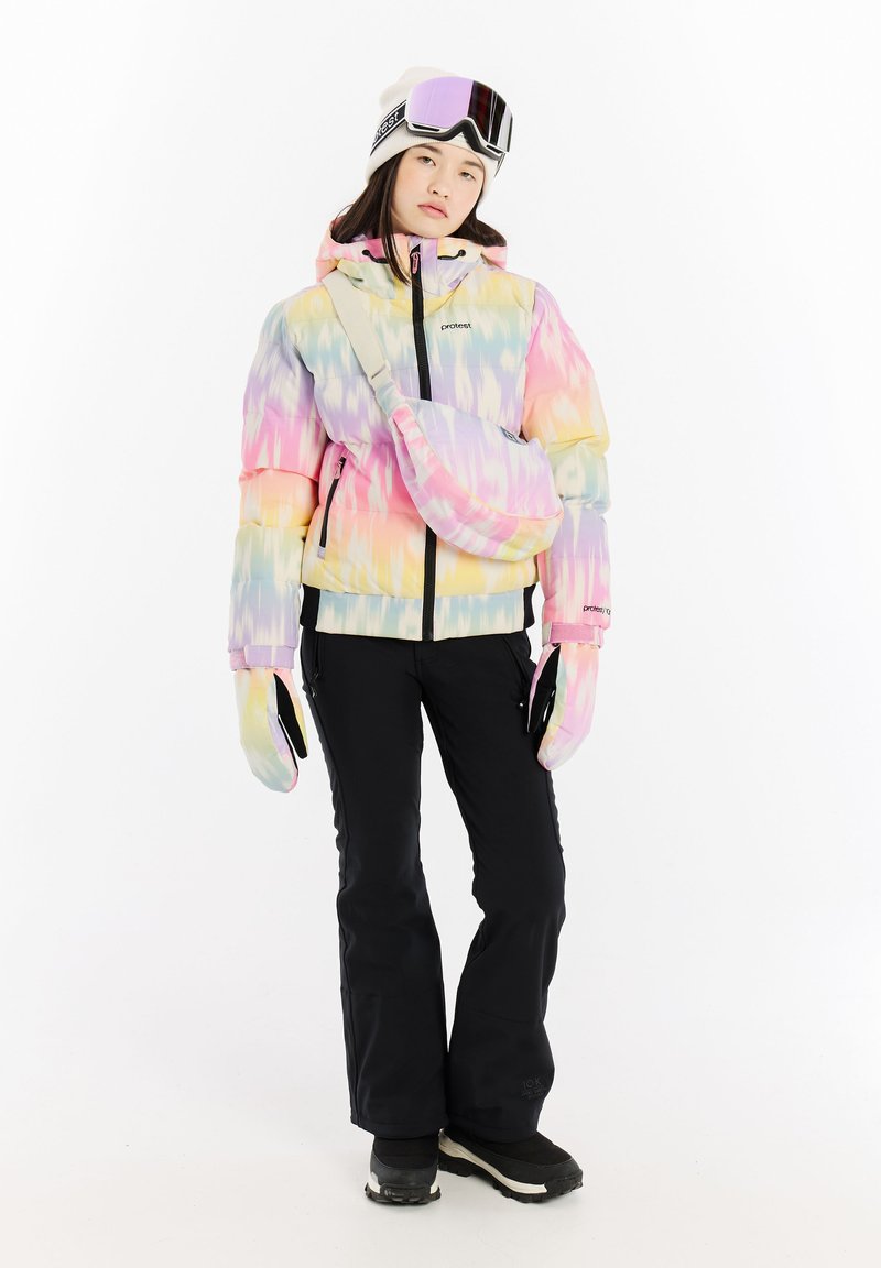 Pestrý páperový kabát s pastelovými gradientnými vzormi, čierne snehové nohavice, rukavice a okuliare. Obsahuje cez rameno tašku a teplú čiapku.