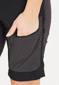 Svarta träningsshorts med en dragkedjeficka, mjuk textur och kontrasterande sömdetaljer. Har ett elastiskt midjeband och logotypaccent.