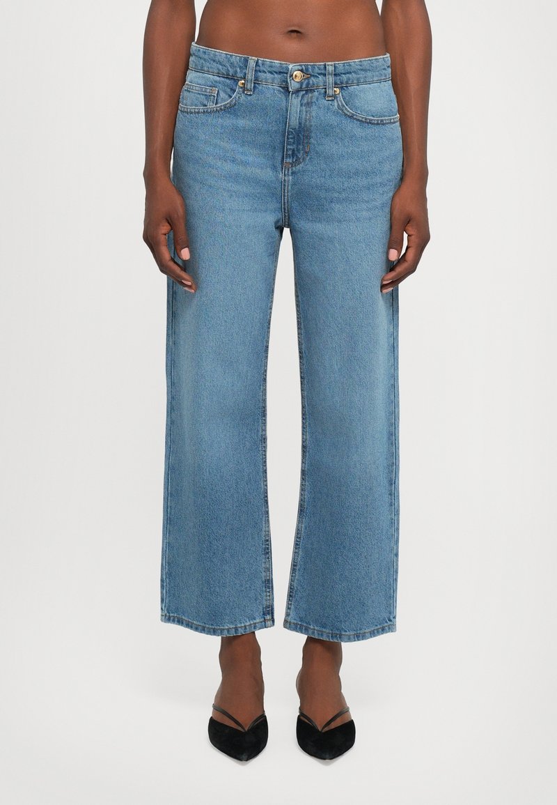 Jeans larges bleu clair à taille haute, avec poches avant, fermeture par bouton et ourlet droit. Fabriqués en tissu denim.