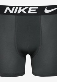 Zwarte Nike boxershorts met een witte elastische tailleband met het 'NIKE' logo. Gladde stof, fitted ontwerp en lengte tot midden boven de dij.