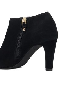 Black suede ankle boot with a high heel, featuring a side zip with gold hardware and smooth texture.