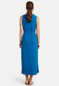 Blue sleeveless maxi dress made of soft fabric, featuring a fitted waist with a belt and side slits for ease of movement.