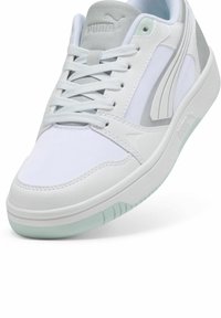 White sneaker with textured leather and mesh upper, featuring gray accents and a mint green outsole. Rounded toe and flat laces.