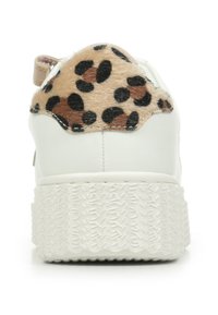 Witte sneaker met dikke, getextureerde zool en een tan-kleurige, leopardprint fluwelen patch op de hiel, van achteraf weergegeven tegen een witte achtergrond.
