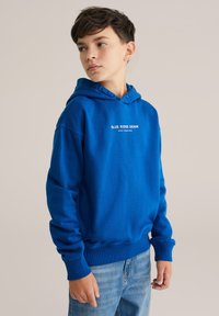 Kék kapucnis pulóver elöl található "BLUE RIDGE DENIM STAY FEARLESS" felirattal, puha anyagból készült, bordázott mandzsettával és aljjal.