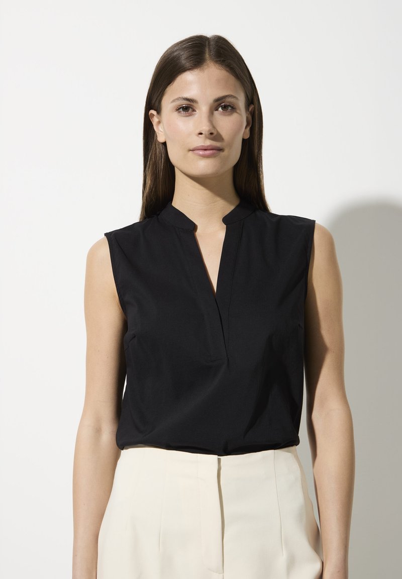 Black sleeveless blouse with a v-neck collar, crafted from smooth fabric, featuring a fitted design and clean lines.
