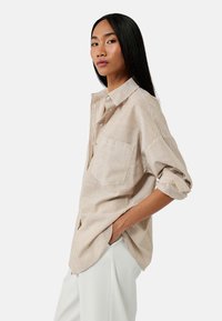 Gestreepte, lichte blouse in beige en wit met een relaxte pasvorm, knoopsluiting aan de voorkant en een enkele borstzak. Opgerolde mouwen en zijsplitsen.