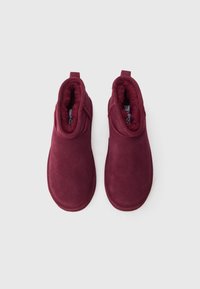 Burgundy nubukist nahkasaapad kunstliku karvaga voodriga, ümar nina ja elastne külg kergeks jalga panekuks. Lamedad tallad koos lihtsa õmblusdetailiga.