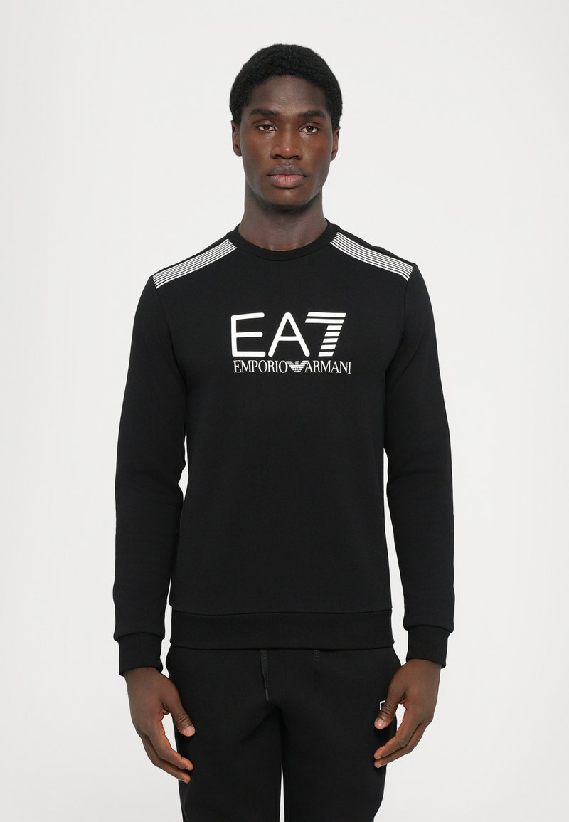 Black sweatshirt with long sleeves, ribbed collar, and cuffs. Features a white EA7 Emporio Armani logo on the front and stripe accents on the shoulders.