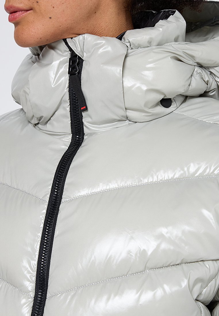 Hellgraue Pufferjacke mit glänzender Oberfläche, hohem Kragen und schwarzen Reißverschlussdetails. Verfügt über gesteppten Bereiche und einen Knopf am Kragen.