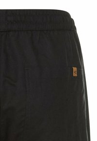 Zwarte shorts met een elastische tailleband, voorzien van een achterzak en een klein bruin logo-label. Soepele stof met een matte afwerking.