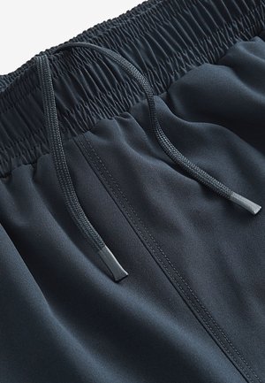 Pantaloncini sportivi blu navy con vita elastica, dotati di coulisse e tessuto liscio e leggero. Dettagli di cuciture evidenti.