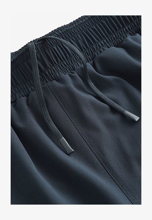 Tmavomodré športové šortky s elastickým pásom, vybavené šnúrkou a hladkou, ľahkou látkou. Výrazné sú aj detaily prešívania.