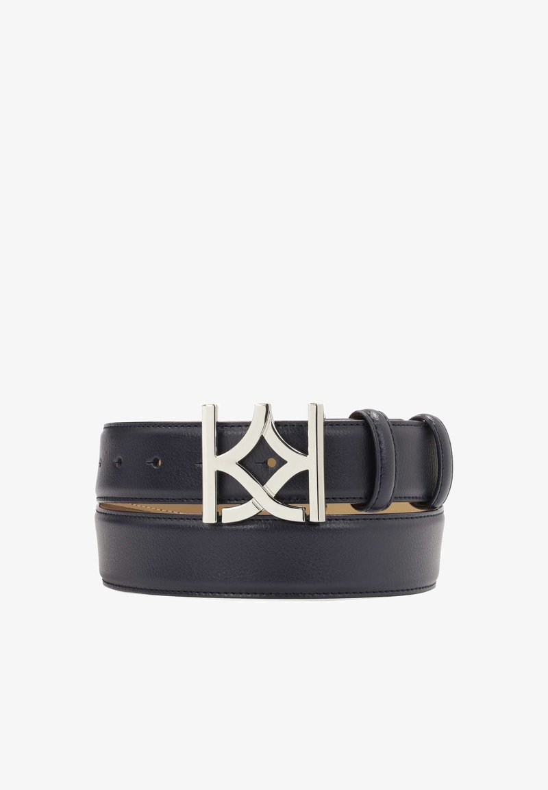 Czarny skórzany pasek z błyszcząca srebrną klamrą w geometrycznym wzorze. Zawiera otwory do regulacji rozmiaru.