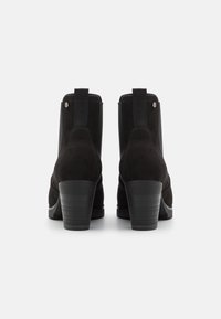 Svarta mockaskor med rund tå, elastiska sidopaneler och klack i staplad design. Enkelt utförande med minimala hårdvarudetaljer.