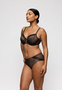 Conjunto de lencería de malla negra que incluye un bralette estructurado con tirantes finos y braguitas de talle alto a juego, que exhiben detalles delicados.