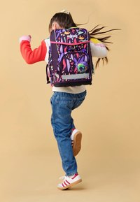 Un sac à dos violet avec des motifs abstraits colorés, des bretelles ajustables, une poche avant et un petit détail de caméléon sur le côté.
