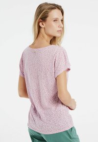 T-shirt rose clair à manches courtes avec un motif léopard subtil et une coupe décontractée, fabriqué en coton doux.