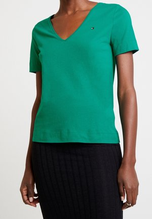 Zielona koszulka z krótkim rękawem w serek, wykonana z bawełny, o slim fit i małym logo przy klatce piersiowej. Gładka tekstura.