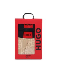 Σετ δύο ανδρικά εσώρουχα boxer Hugo σε μπεζ και μαύρο με κόκκινες λάστιχες μέσης με το λογότυπο, συσκευασμένα σε κόκκινη συσκευασία λιανικής με λαβή.
